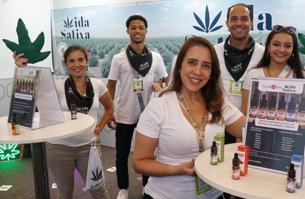 Equipe da Vida Sativa no estande da empresa, ao lado de expositores com óleos de CBD